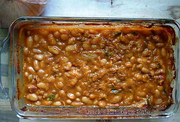a dish filled with beans and meat next to a plate with garlic