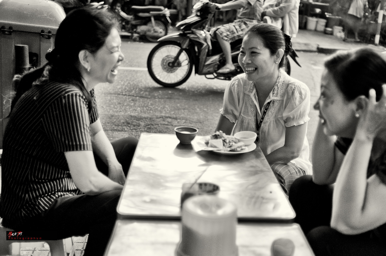three woman smiling as they sit outside a cafe