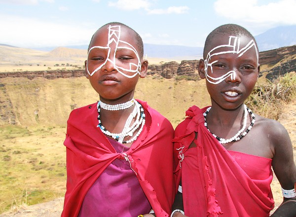 two children dressed up with white painted faces in front of a mountain