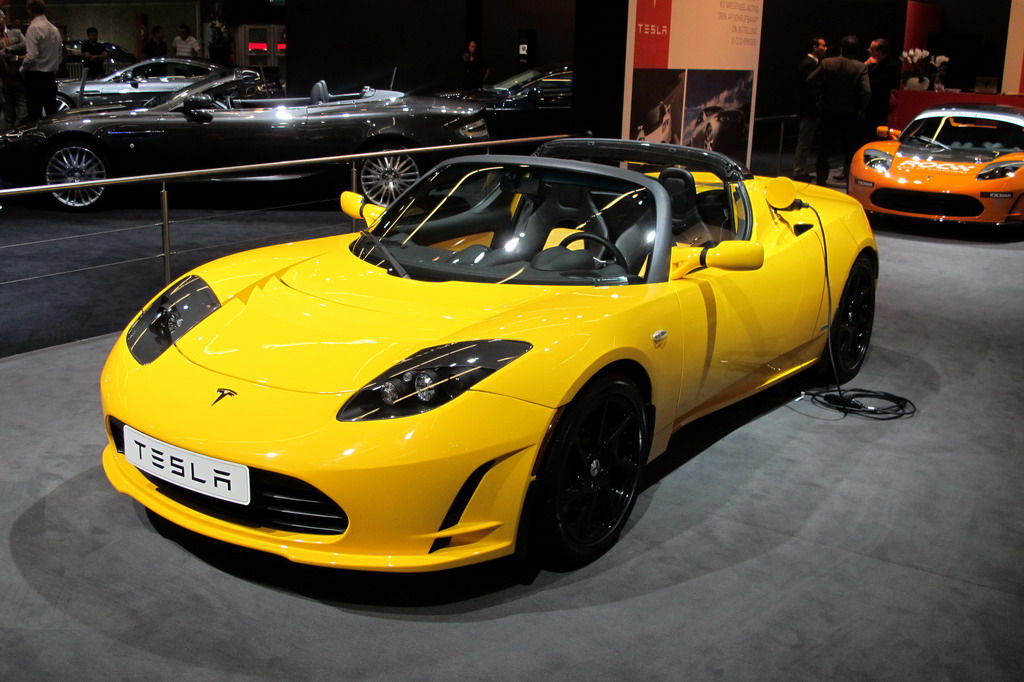 two yellow sports cars parked on display at a car show