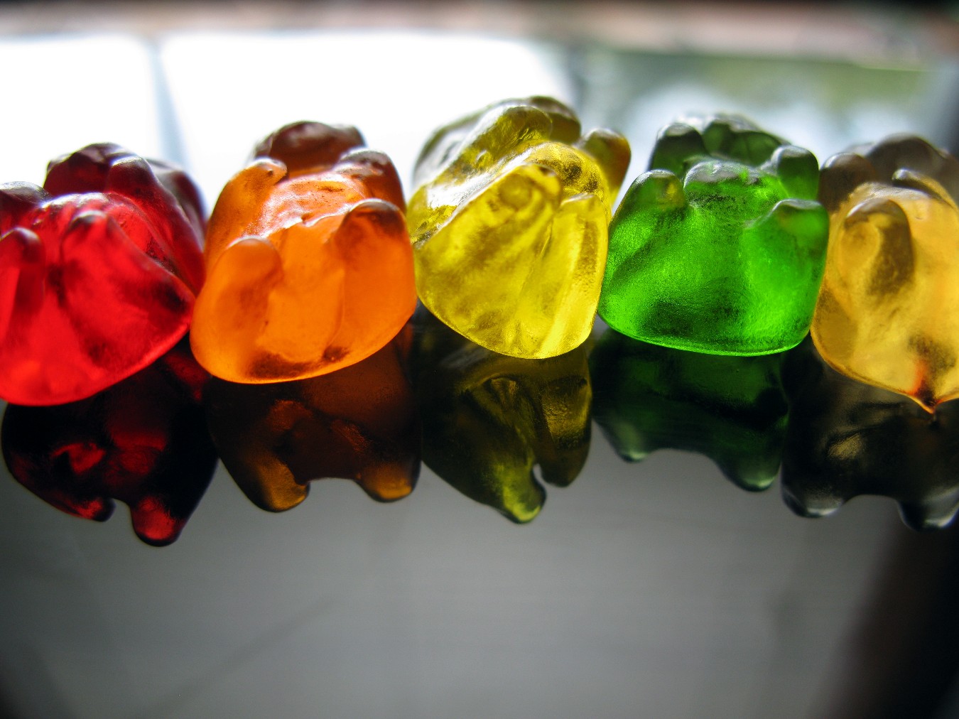 a row of gummy bears are reflected in water