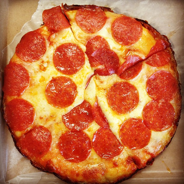 pepperoni pizza in an open cardboard box with other food items