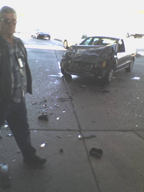 a man standing next to a car that had been hit by another car
