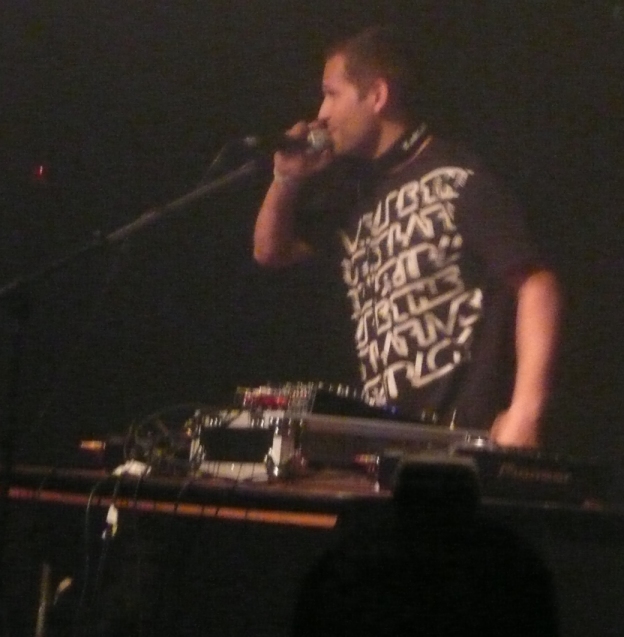 a man holding a microphone while standing next to a keyboard