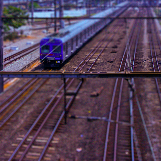a purple and blue train traveling down tracks