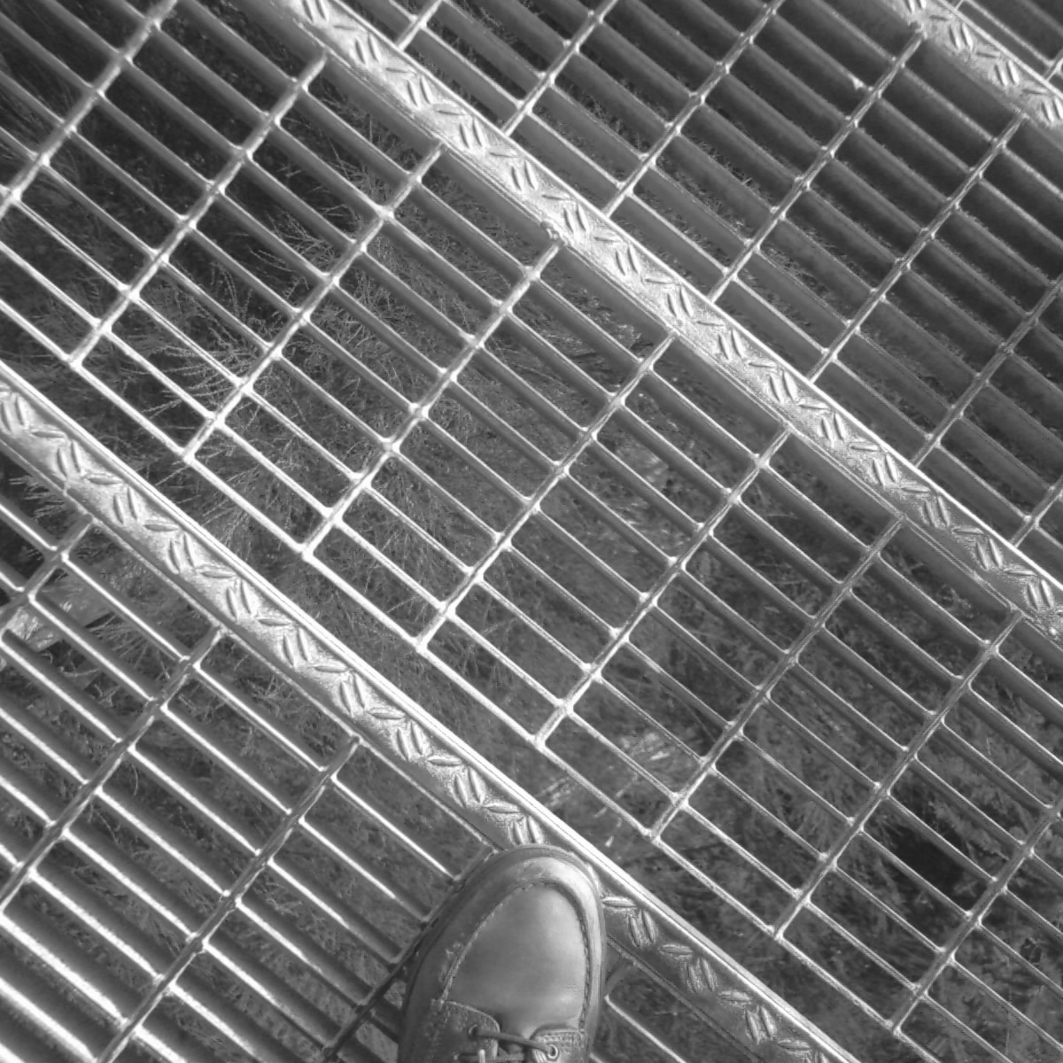 a person's shoes are placed near a large metal grate