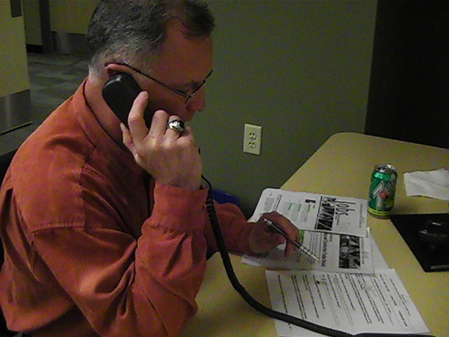 a man sitting at a table holding a phone to his ear