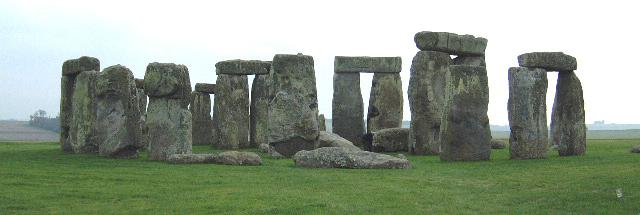 two people walking past a large group of carved stones