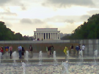 many people are walking by the water fountains in front of a monument