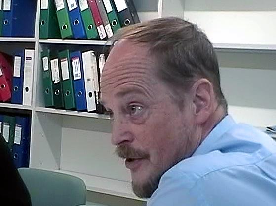a man with a moustache and mustache sitting in front of some folders