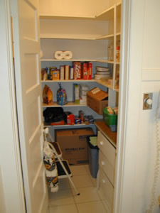 a narrow pantry area with white cupboards, open shelves, and open shelves