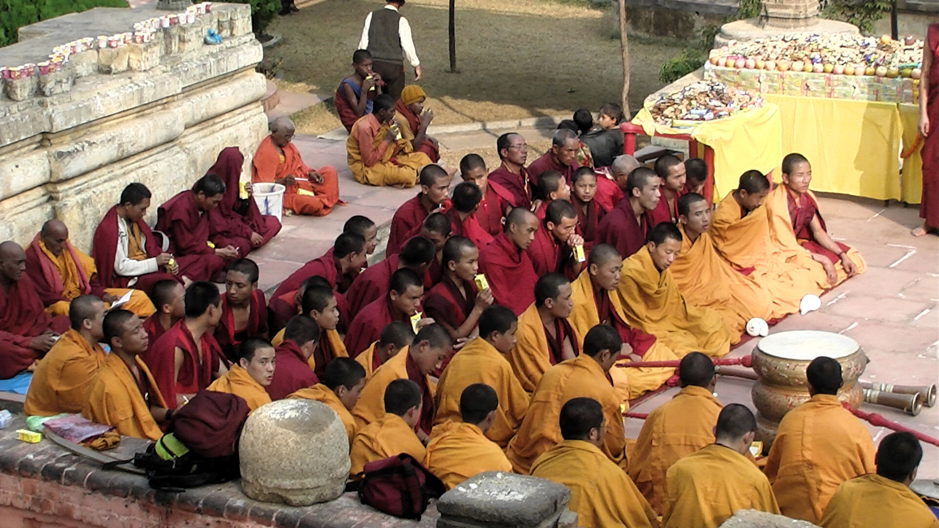 many monks are gathered at a corner, sitting and listening