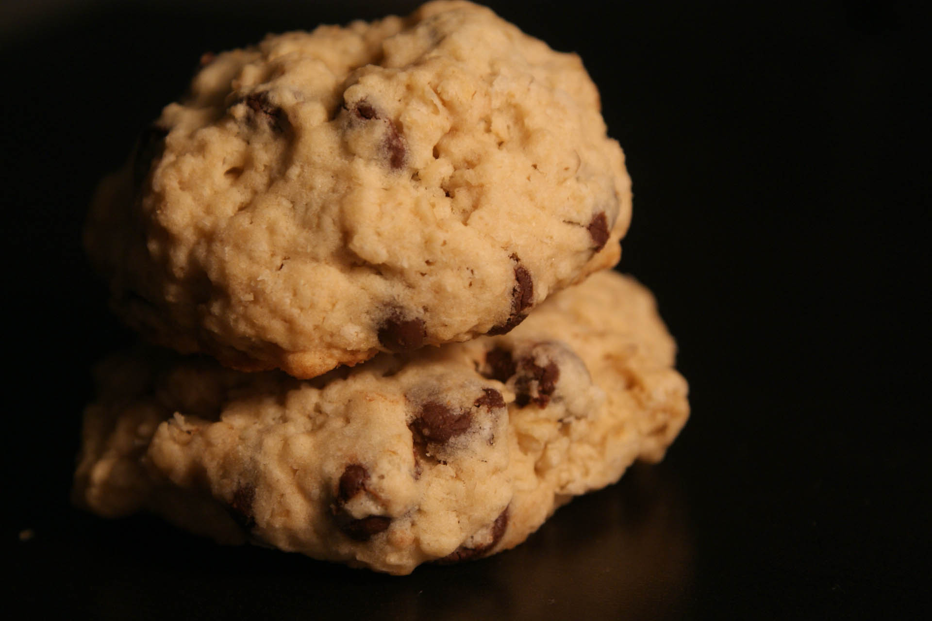 a close up of three cookies with cranberries on a black background