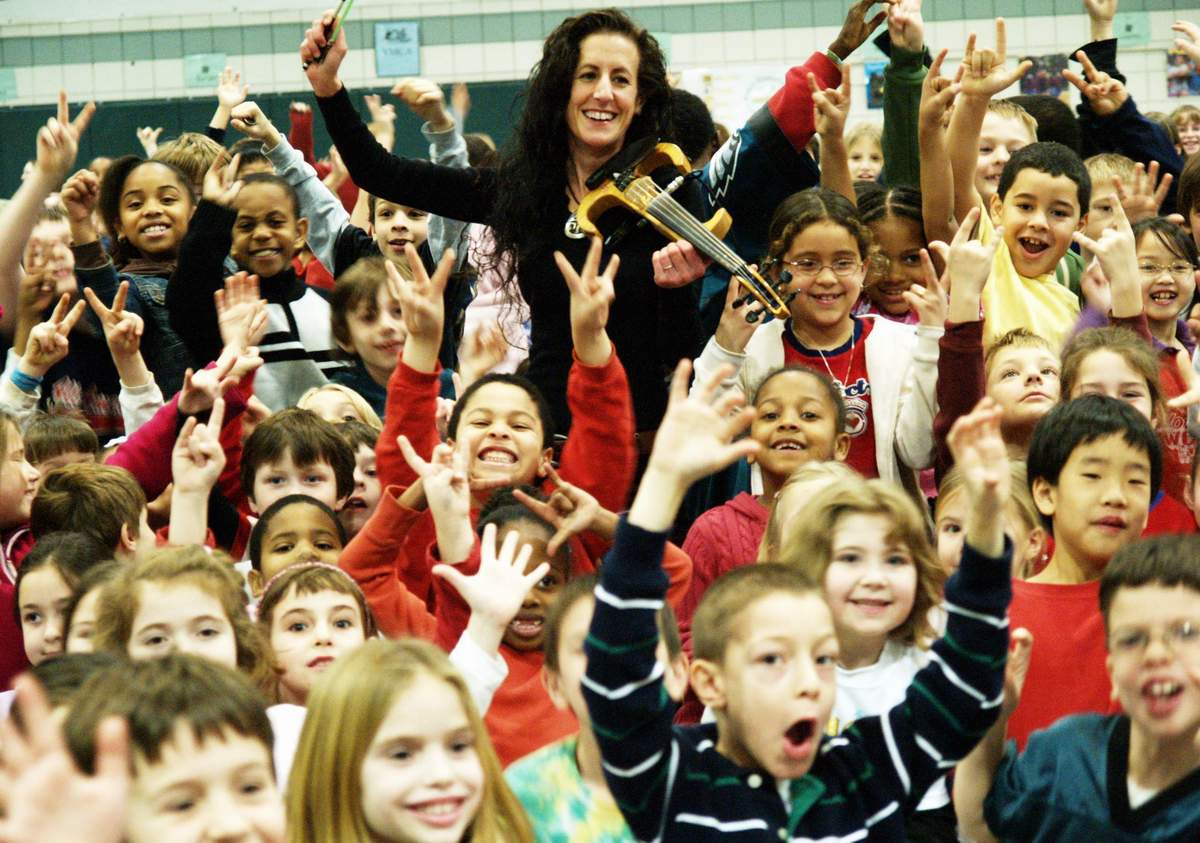 several children are in a gym with one person playing violin