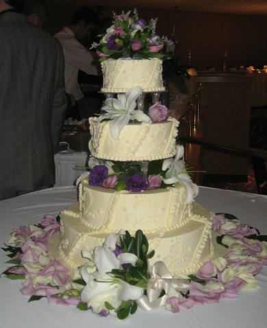 a three tiered wedding cake with lots of flowers on the table