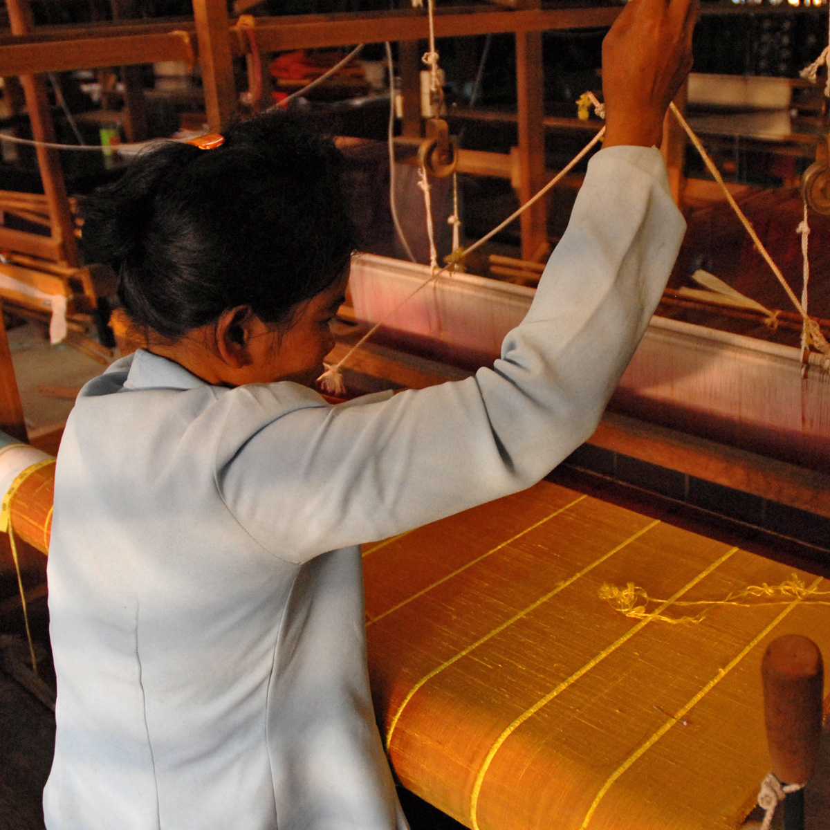 an asian woman in white jacket and jeans working with weaving machine