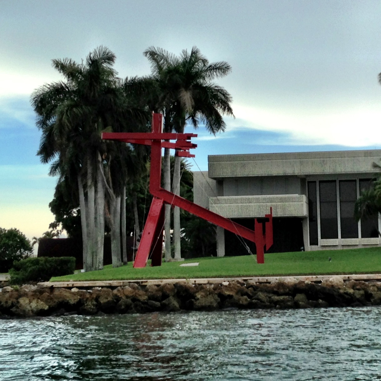 red sculpture on the side of a body of water