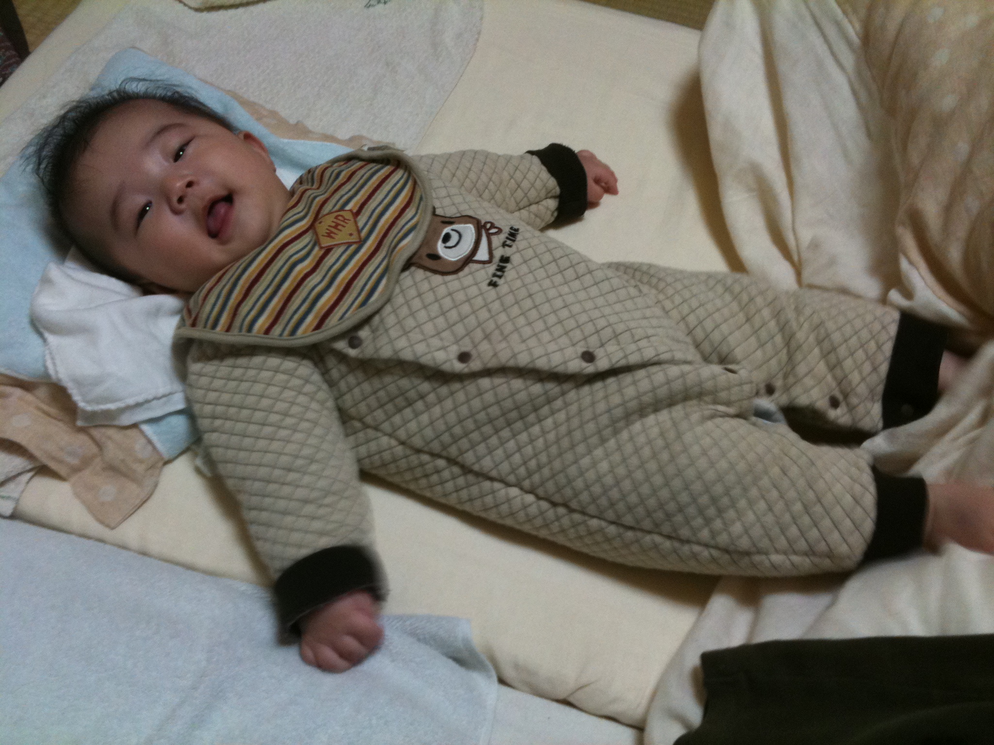 a baby lying on a bed holding a mitt