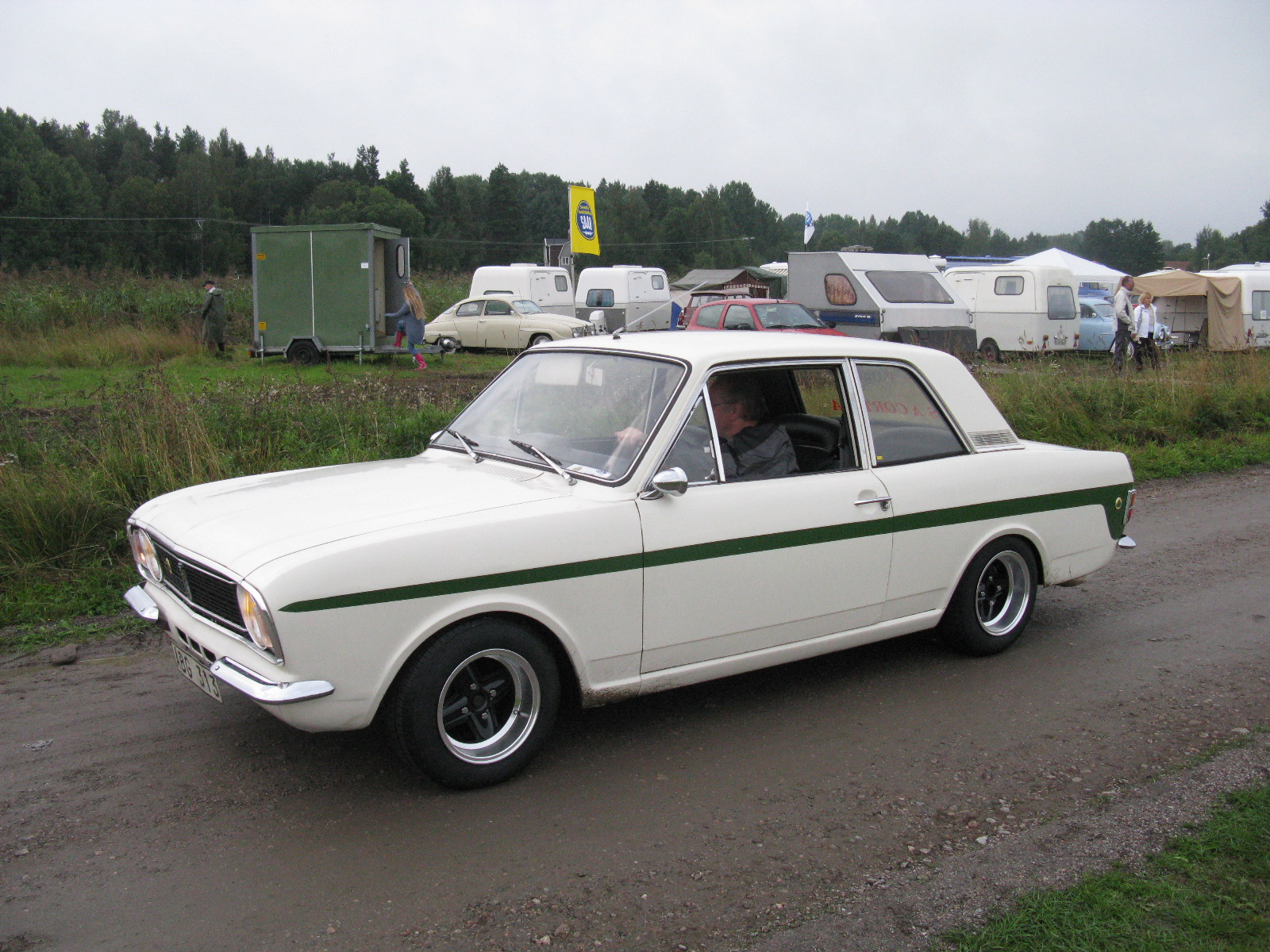 a white and green car driving down a country road