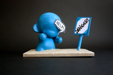 a blue figurine in the shape of a person with the word news on his face next to a sign