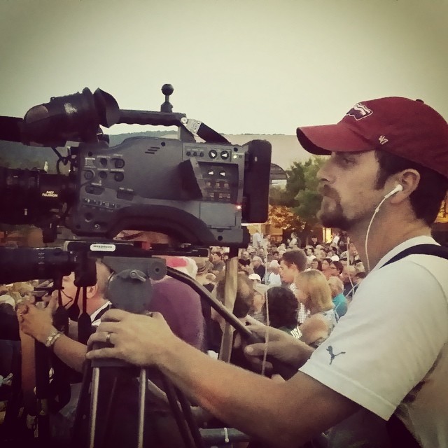 a man in red hat standing next to a camera