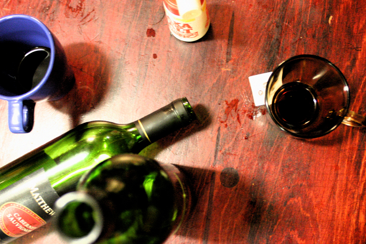 two wine glasses and two bottles are sitting on a wooden table