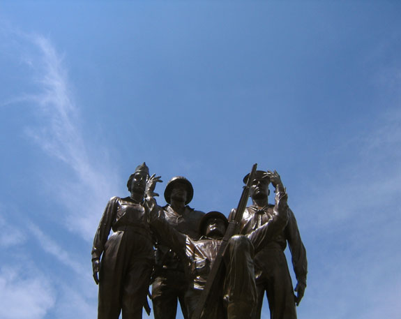 a statue of three men looking up to a sky