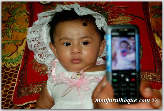 baby wearing a dress and holding a cell phone