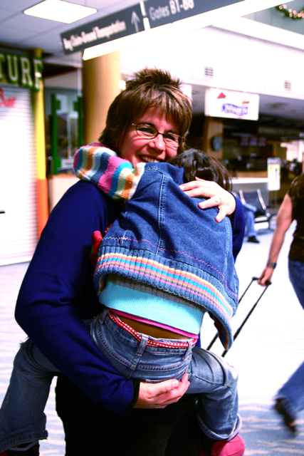 a woman is carrying a small child on a luggage bag