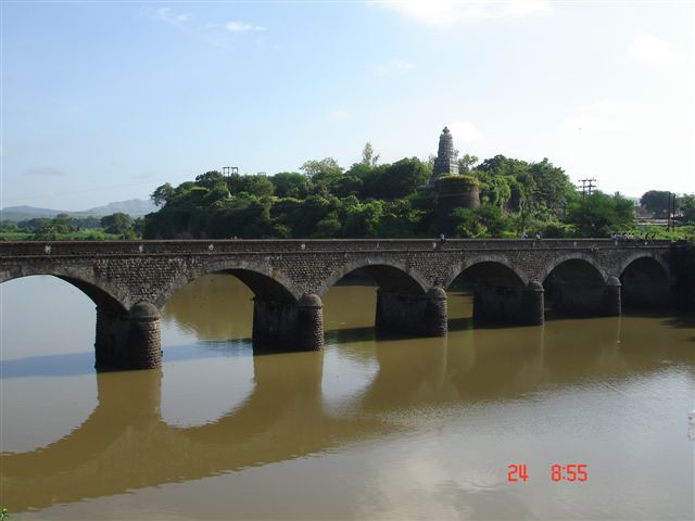 a bridge crosses over water with an island in the distance