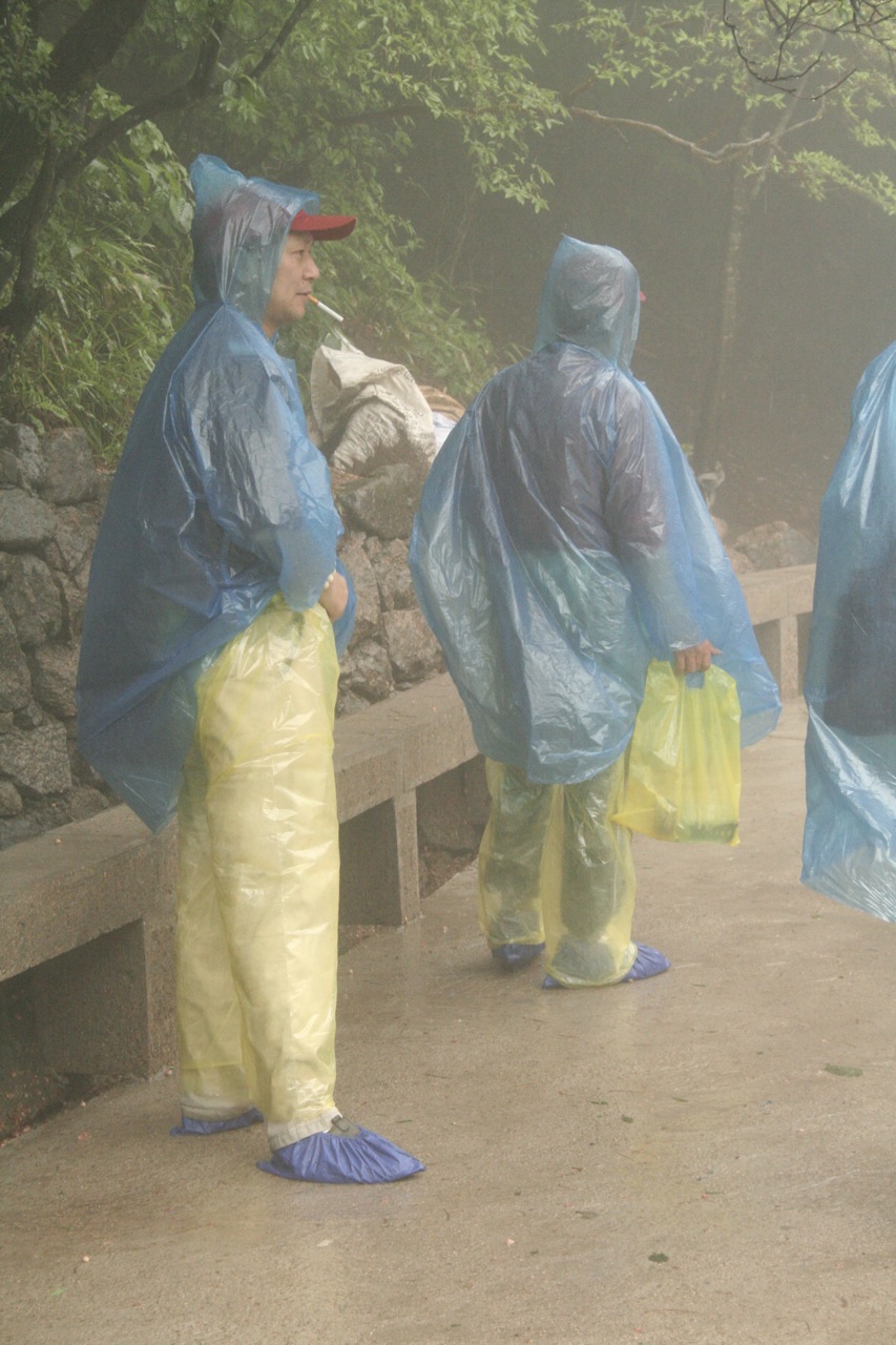 three people walking down the street covered in plastic