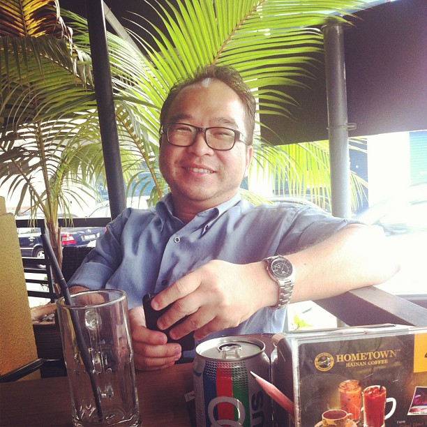 man in a blue shirt and glasses eating with a soda
