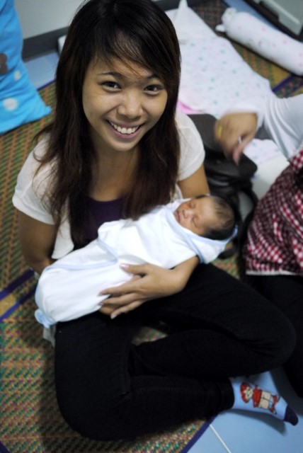 a smiling lady with baby on her lap