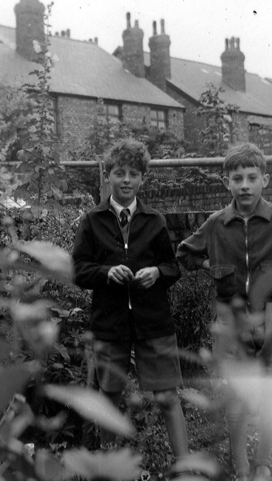 two boys with brown shorts in front of a brick house