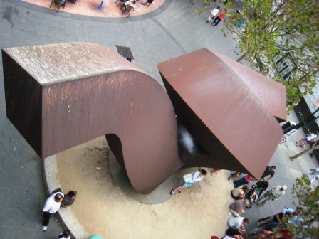 a group of people are standing next to the sculpture