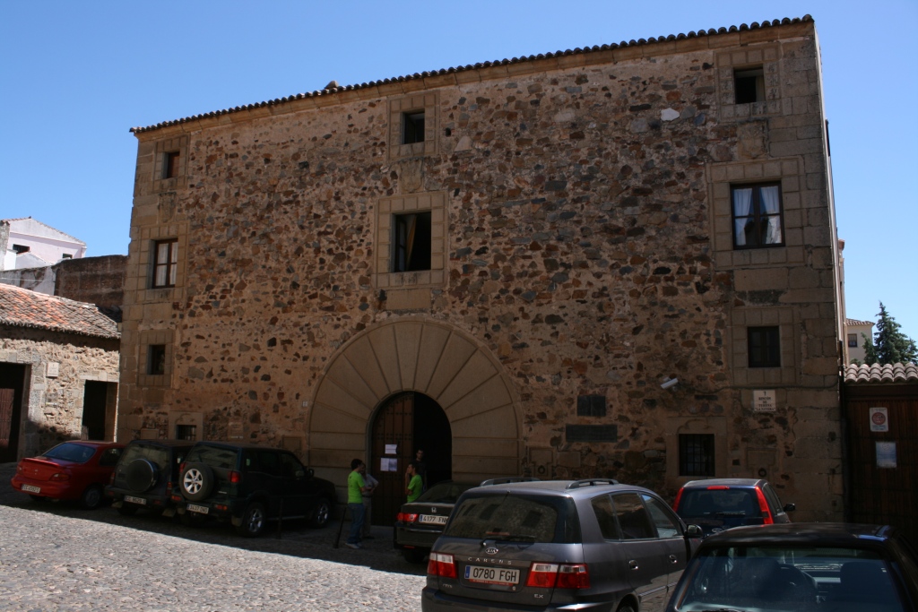 three cars are parked in front of an old brick building