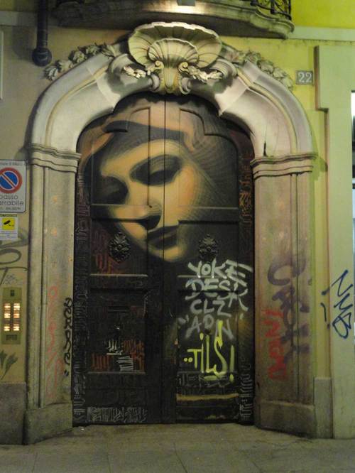 a wall with graffiti on it and an arched doorway in the center