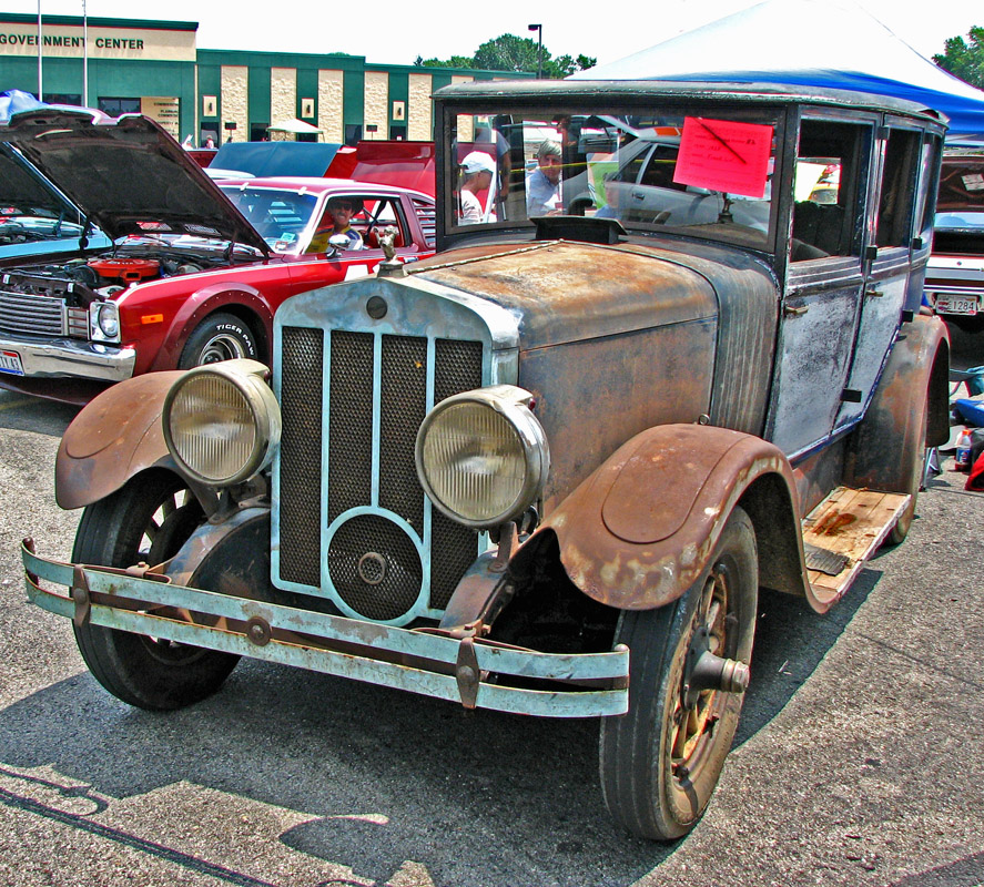 an old pickup truck is parked by a car show