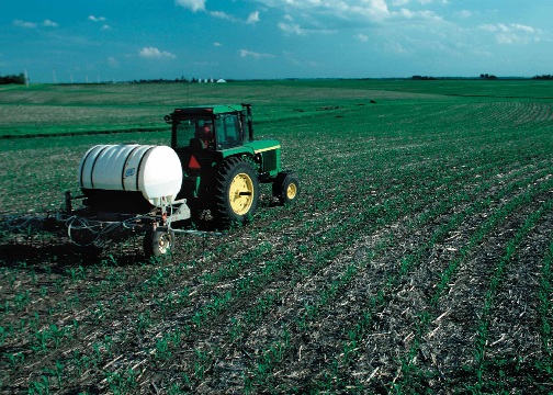 a green tractor with water tank on an empty field