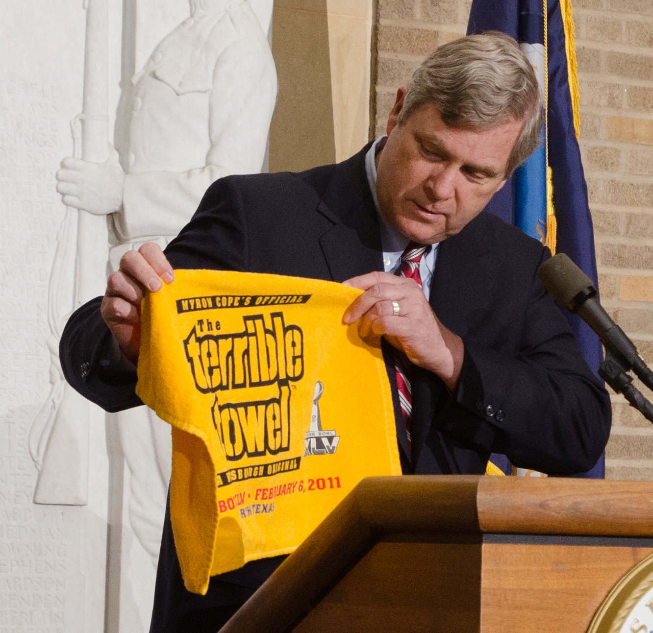 a man standing in front of a podium holding up a yellow bag