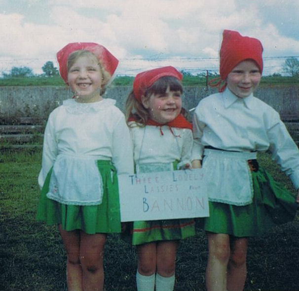 three young children with hats holding a sign