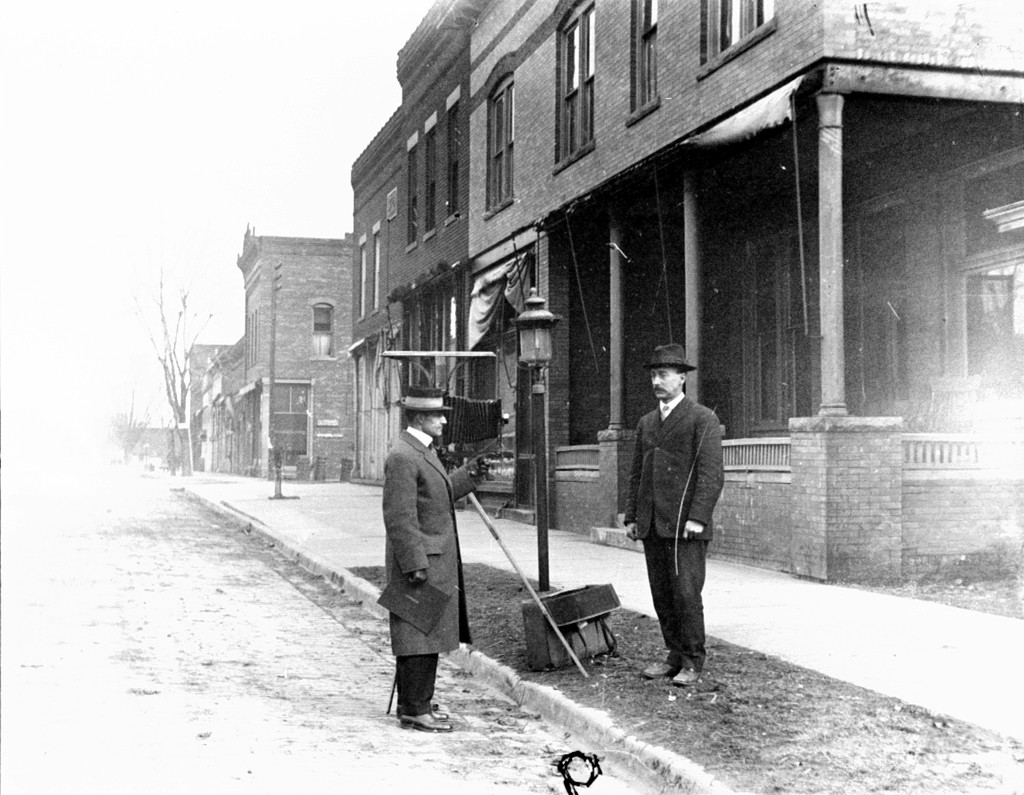 two men are talking in front of an old fashioned street