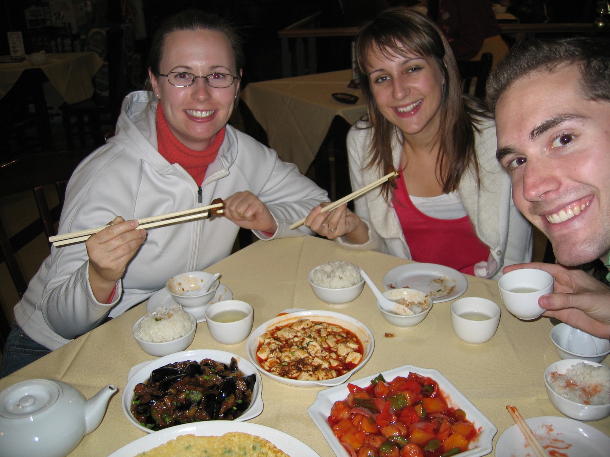 two adults posing for the camera with many foods in front