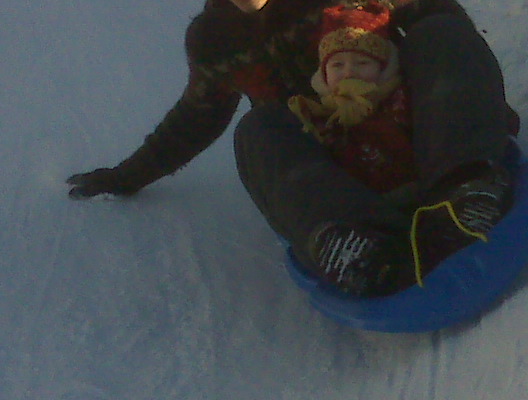 a little child sledding down a hill with a hat on