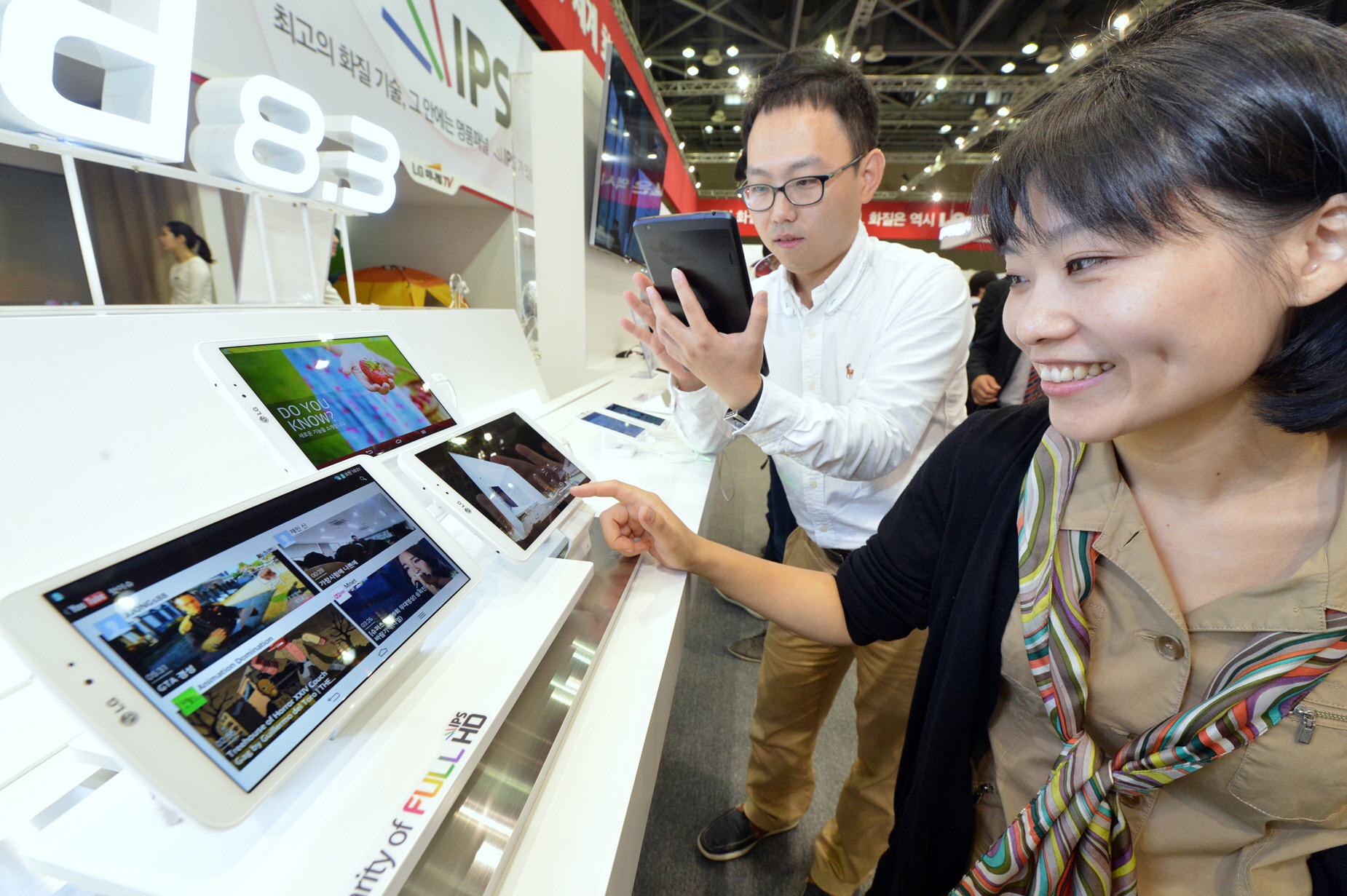 an asian woman at a technology show looking at a tablet