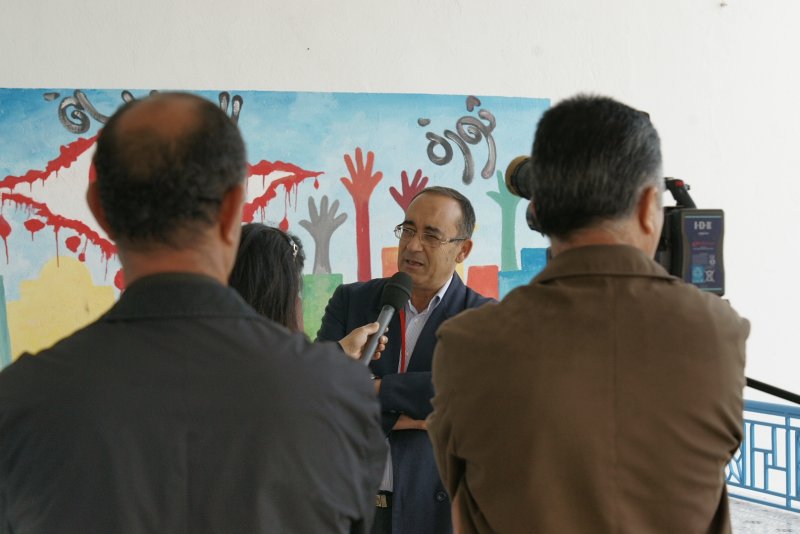 man holding microphone in front of painting at event