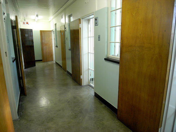 a long hallway with three closed doors, and a window in the center