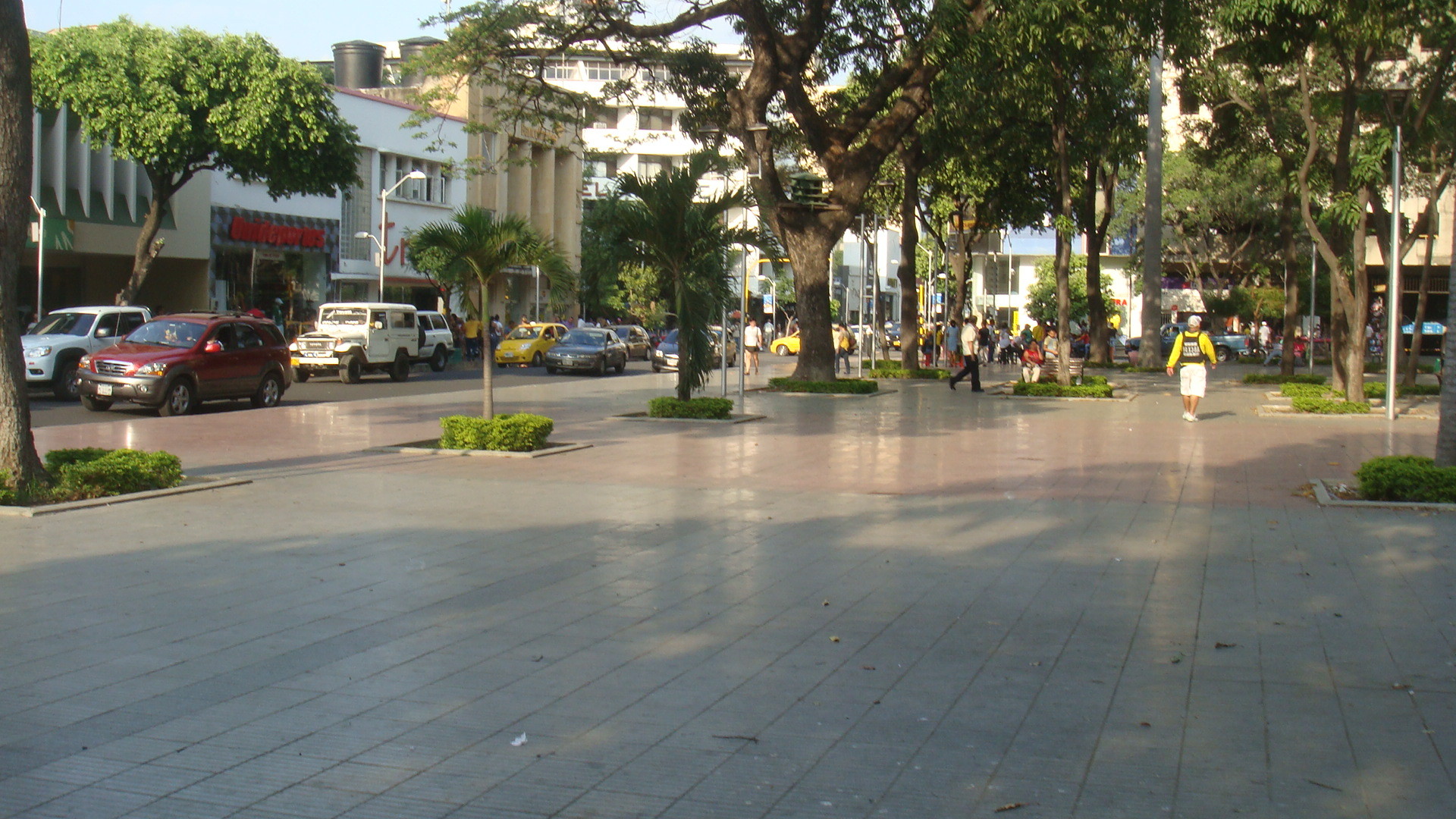 a city block area with buildings, people walking around and cars parked on the road