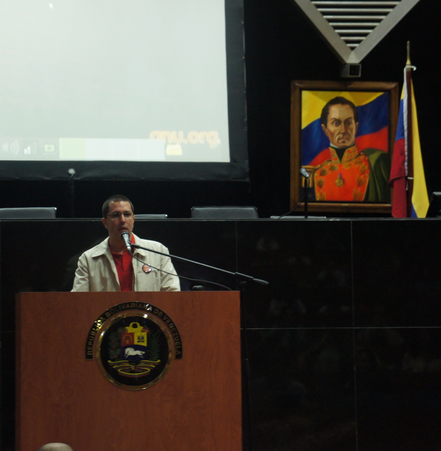 a man that is standing at a podium near a flag