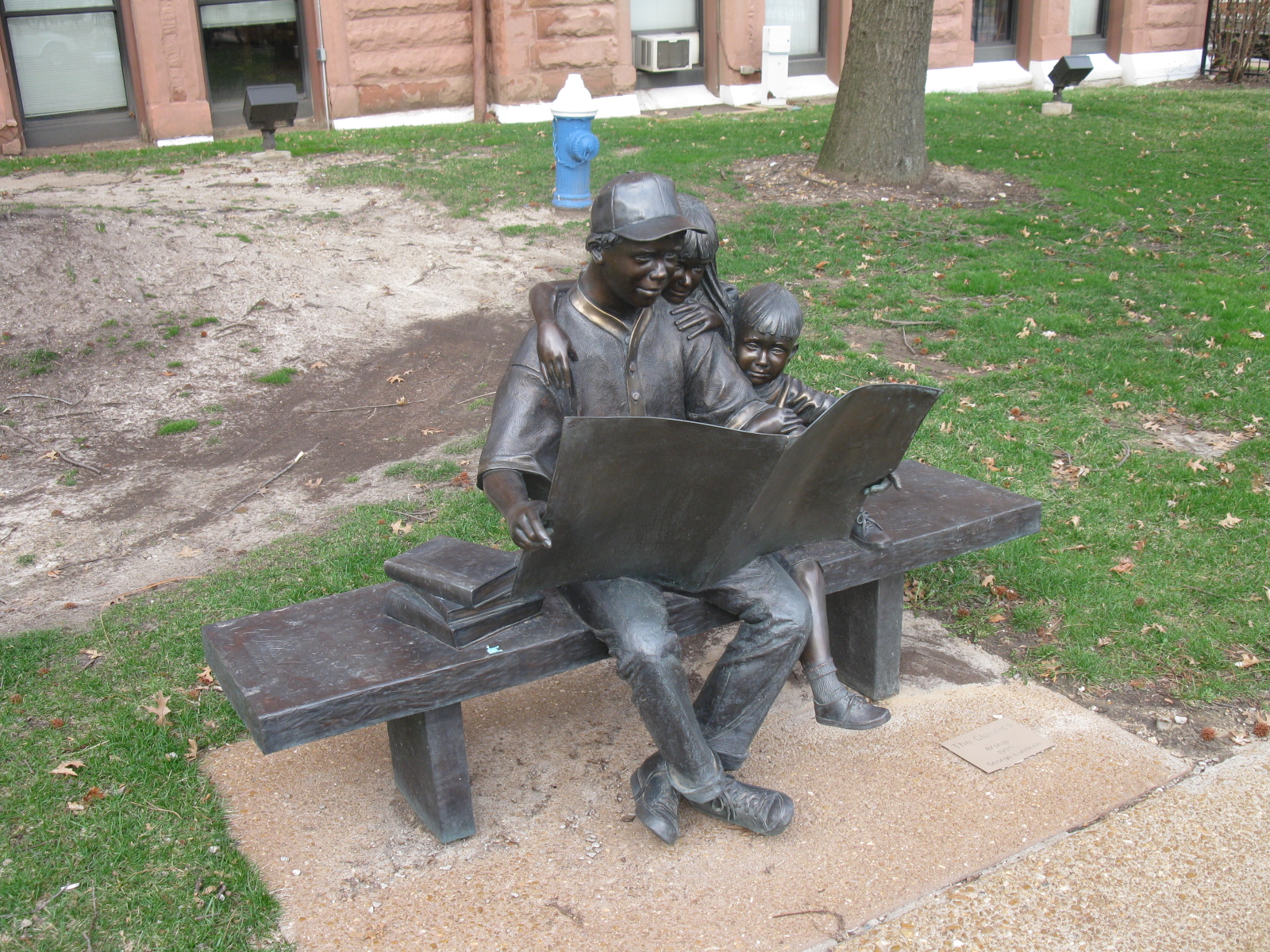 a statue of a man sitting on a bench next to two children